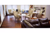 Interior view of a lounge with round tables, upholstered chairs, and a brown leather sofa.