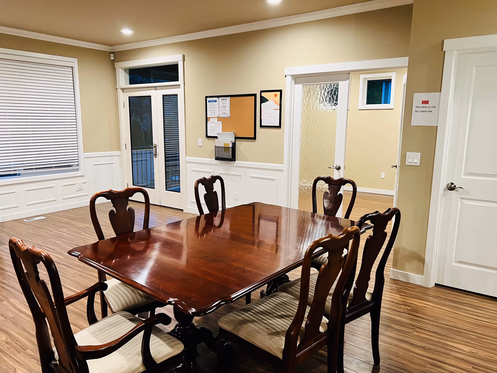 A wooden dining table and chairs in a bright, wainscoted dining room.