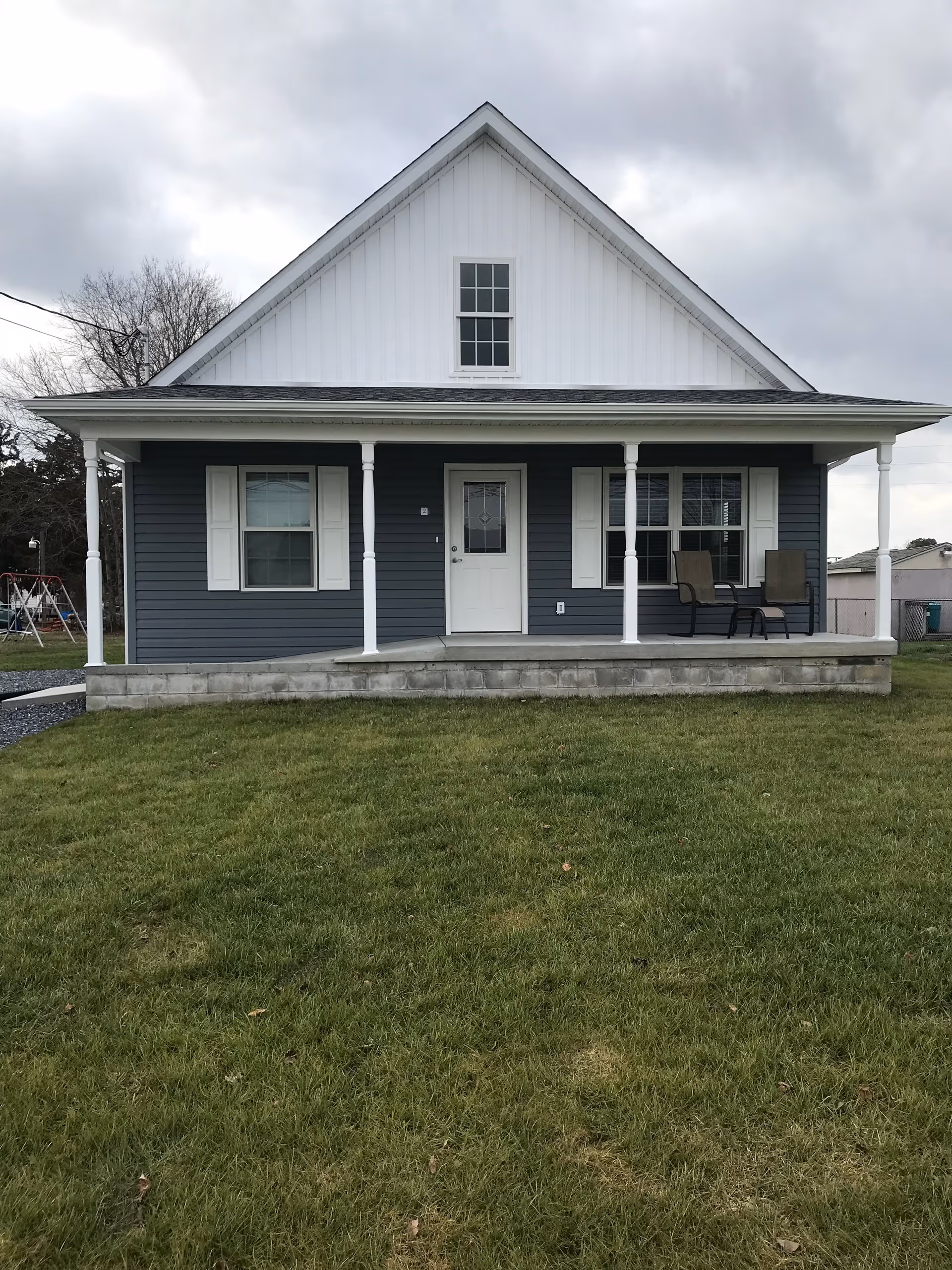 A small blue house with a porch and white columns on a grassy lawn.