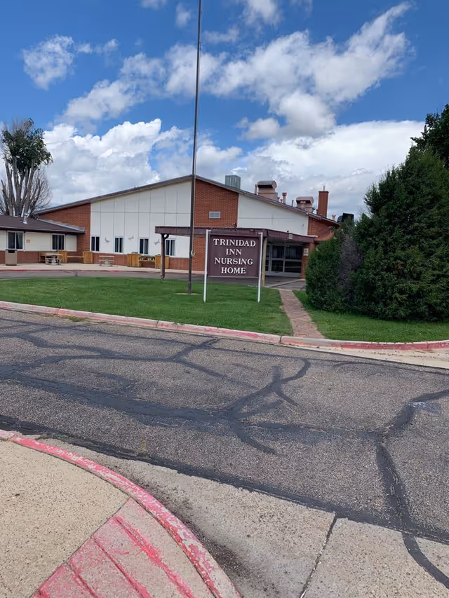 Exterior front view of Trinidad Inn Nursing Home with its entrance sign on a grassy lawn and a paved driveway.