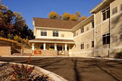 Exterior view of Comforts of Home Advanced Assisted Living entrance with parking and autumn trees