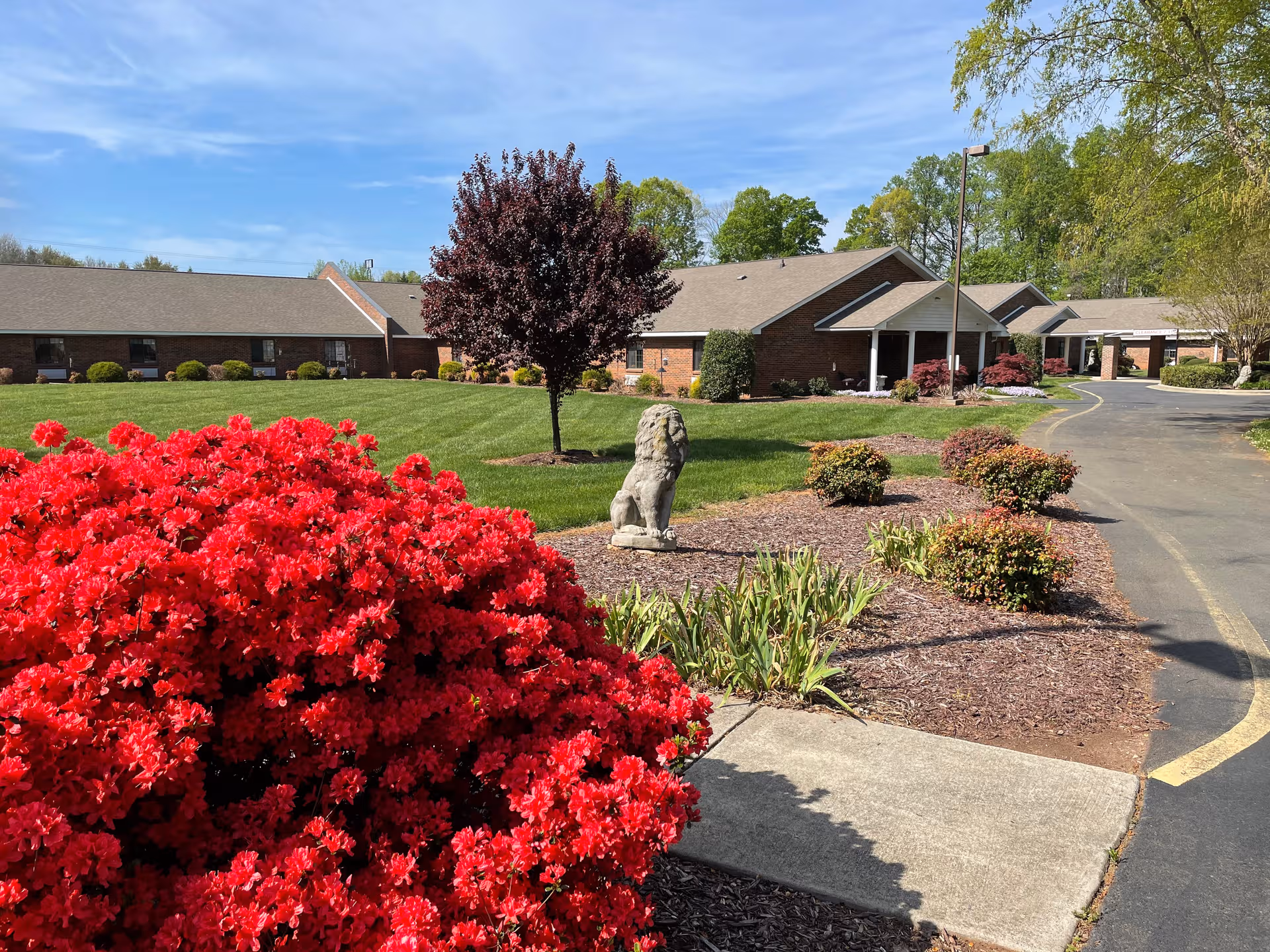 Exterior view of Peak Resources Brookshire with brick building, landscaping, and red flowering bushes in foreground.