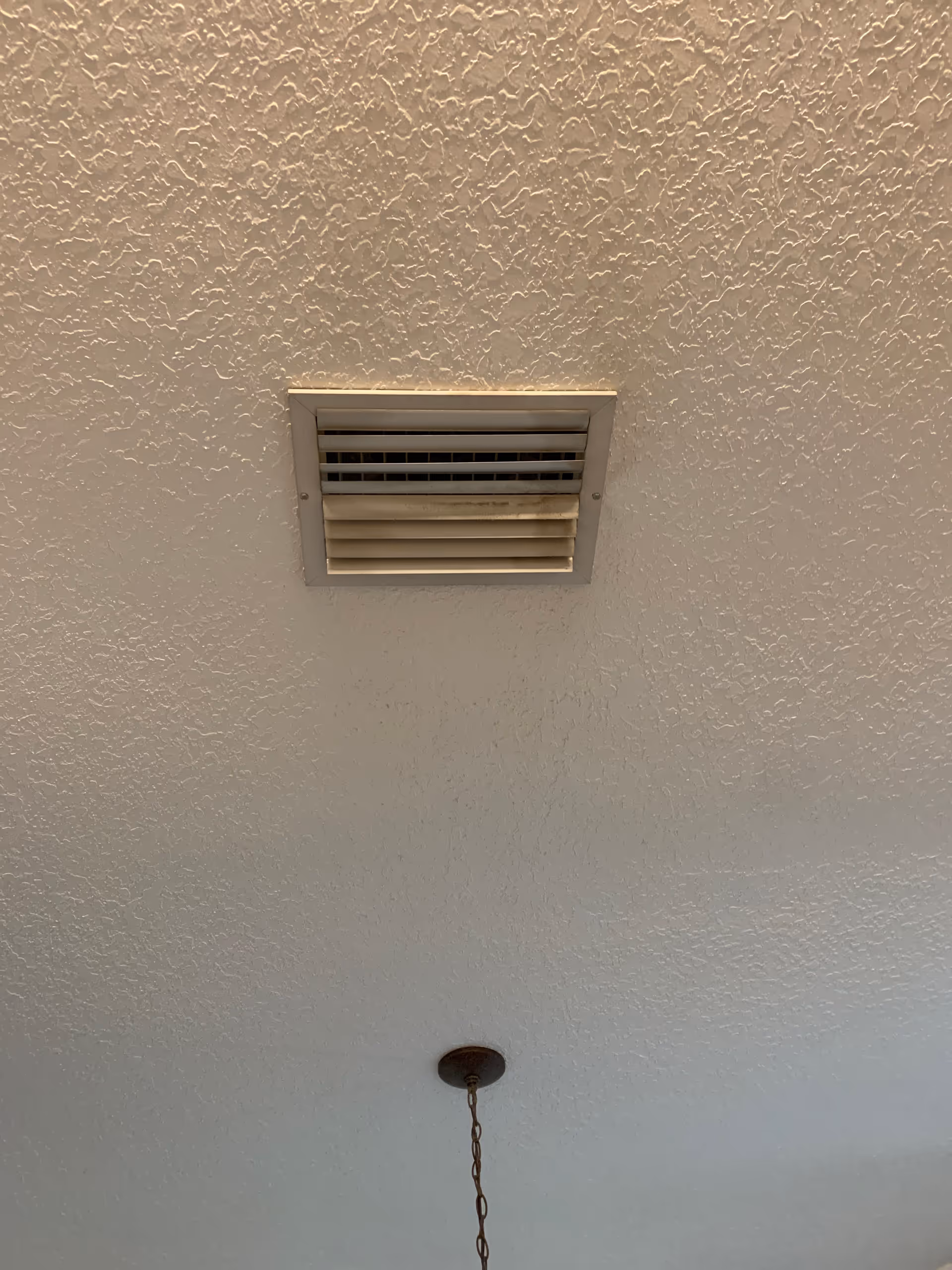 Textured white ceiling with a square vent and a hanging chain light fixture.
