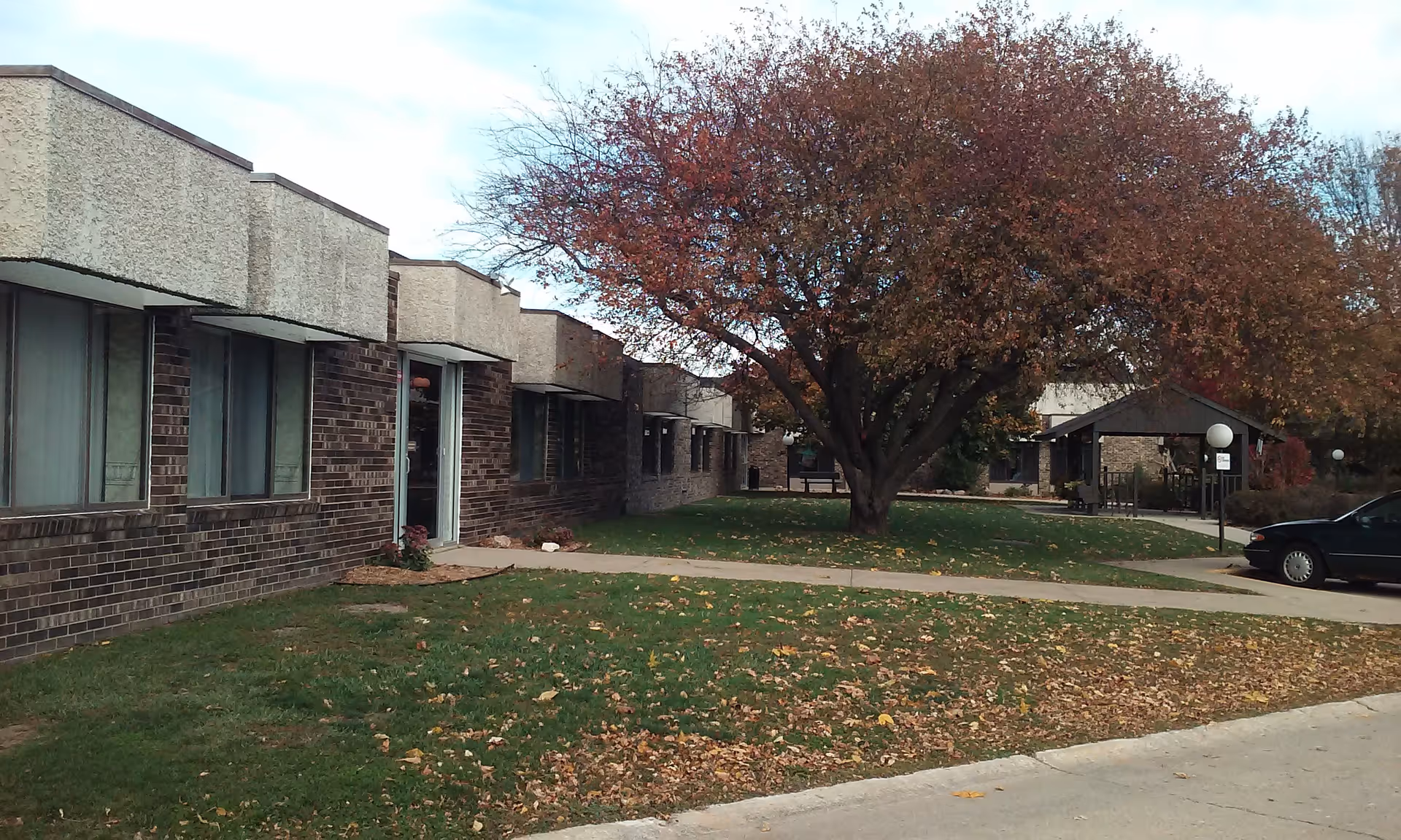 Exterior view of Accura HealthCare of Carroll with a tree, walkway, and lawn.