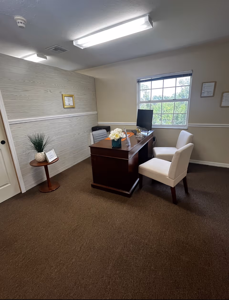 Reception office inside Molina Home Care with dark wood desk, computer, white chairs, and window.