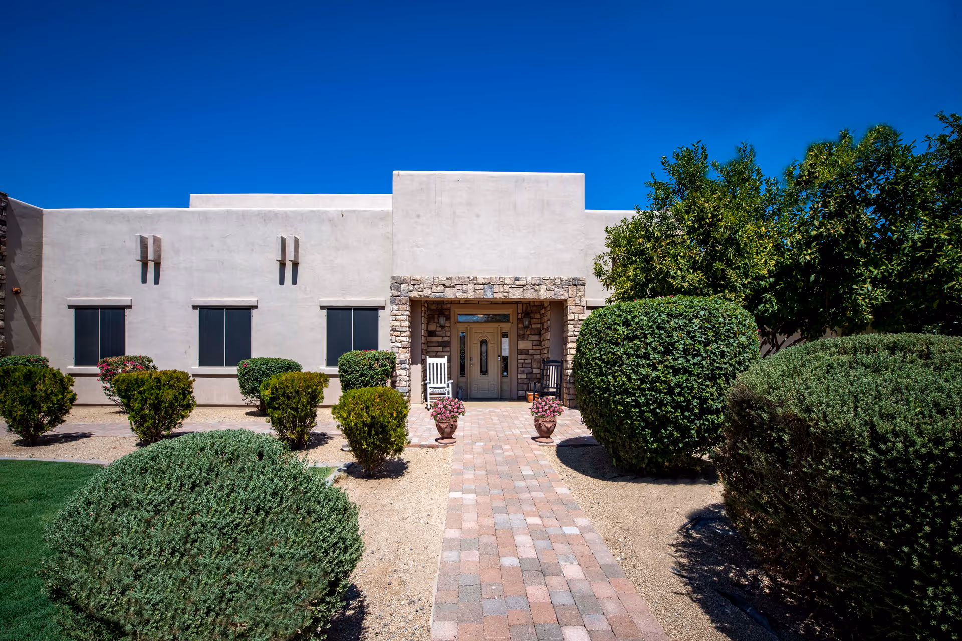 Sunny exterior view of Palmaritas Home Care entrance with desert landscaping