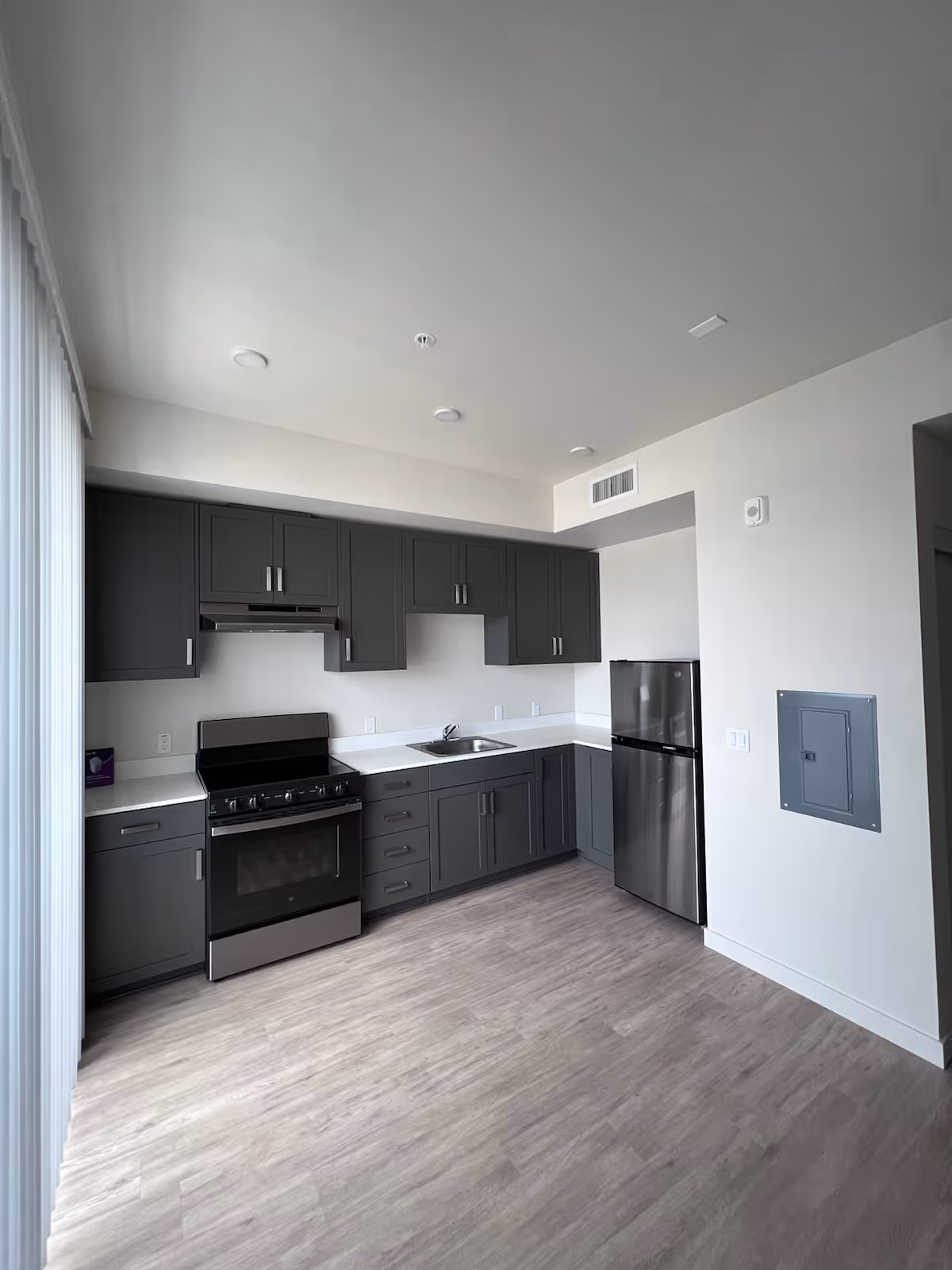 Modern gray kitchen with stainless steel appliances, sink, and white countertops.