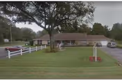 Country Manor Assisted Living exterior: single-story building with green lawn, trees, and parked cars.