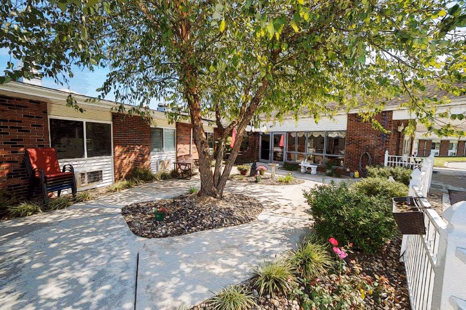 Outdoor courtyard at Woodland Hills facility with central tree, benches, and garden beds.
