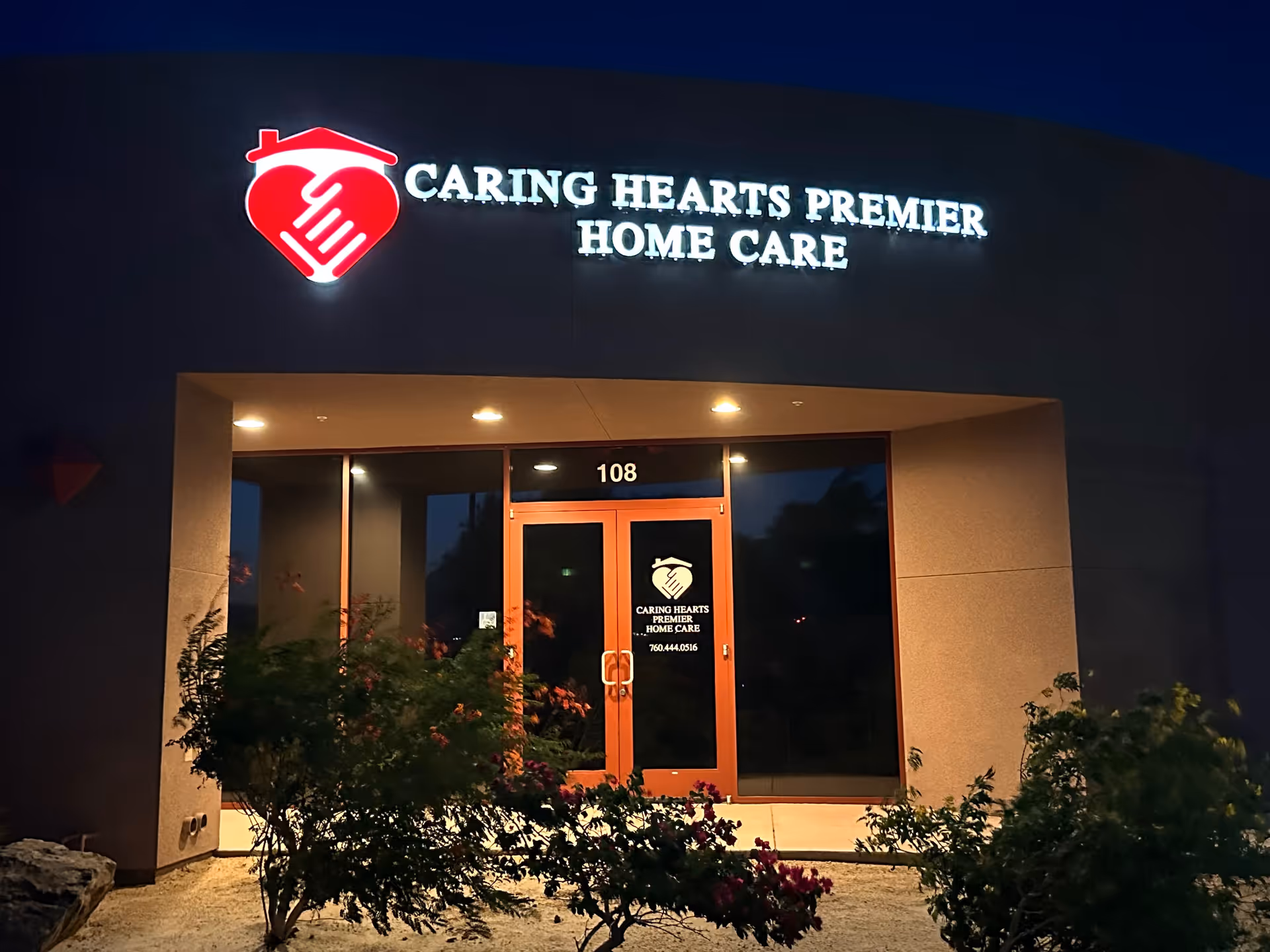Night exterior of Caring Hearts Premier Home Care entrance with illuminated sign.
