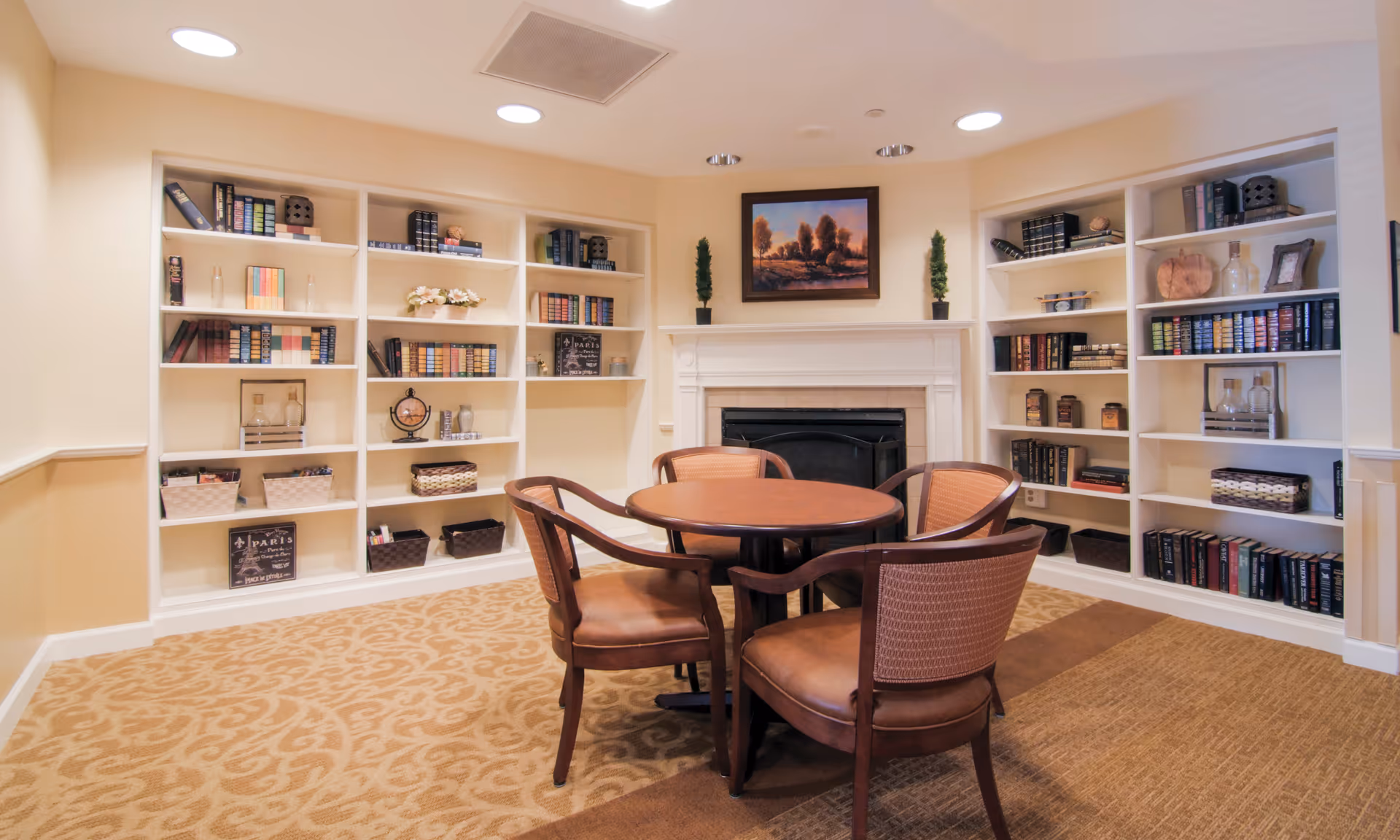 Cozy interior lounge with built-in bookshelves, a circular table, and a fireplace.