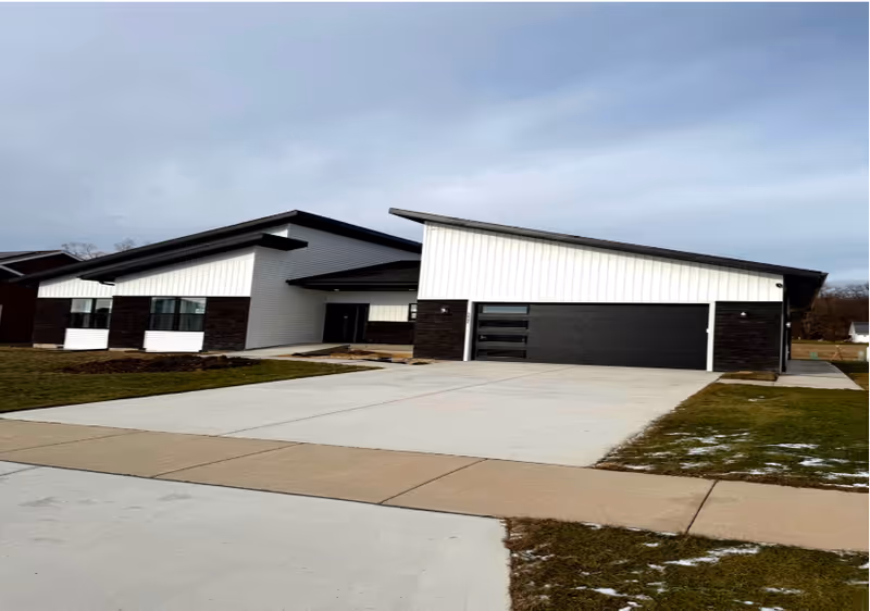 Modern single-story facility exterior with a wide driveway and black garage doors.