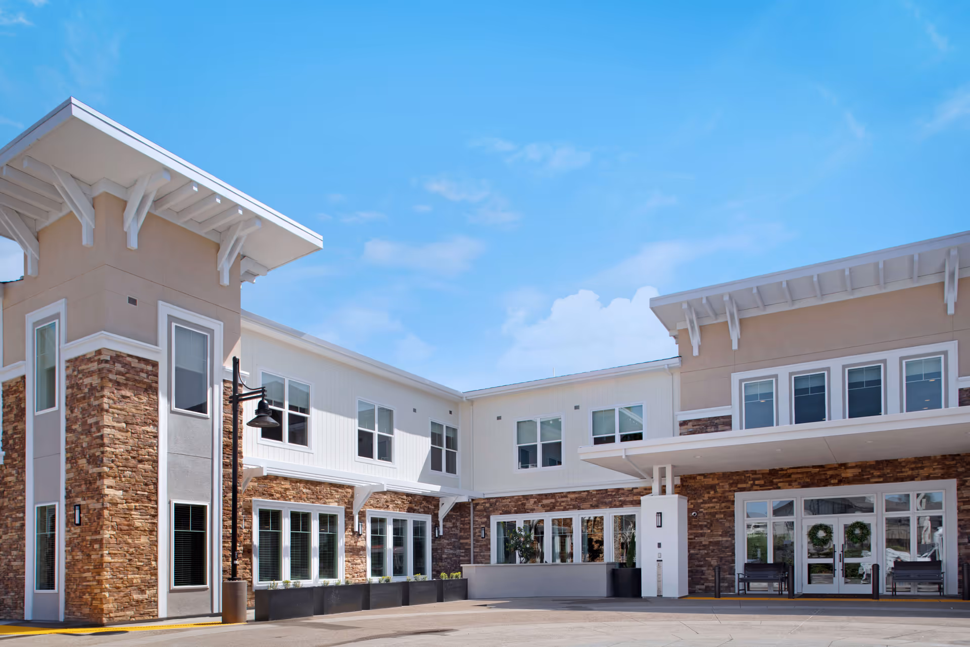 Sunny modern senior living facility exterior with brick accents and large glass doors.