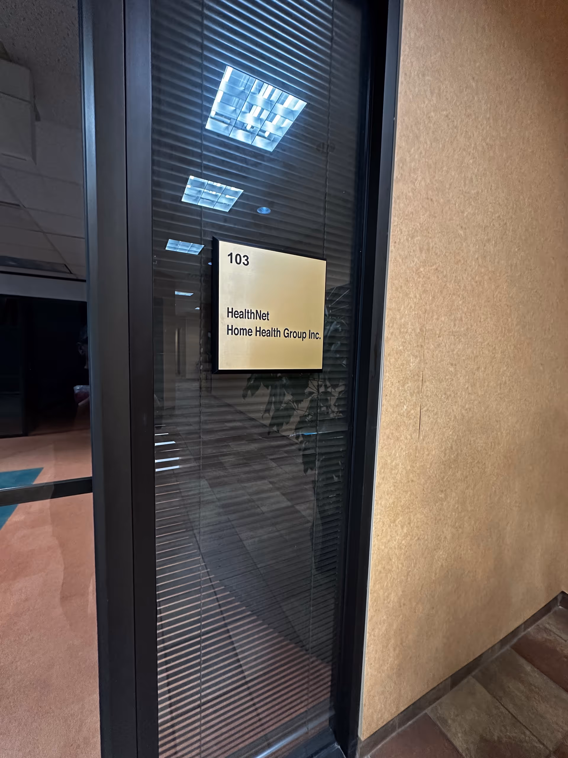 Glass door with sign reading HealthNet Home Health Group Inc. in a hallway.
