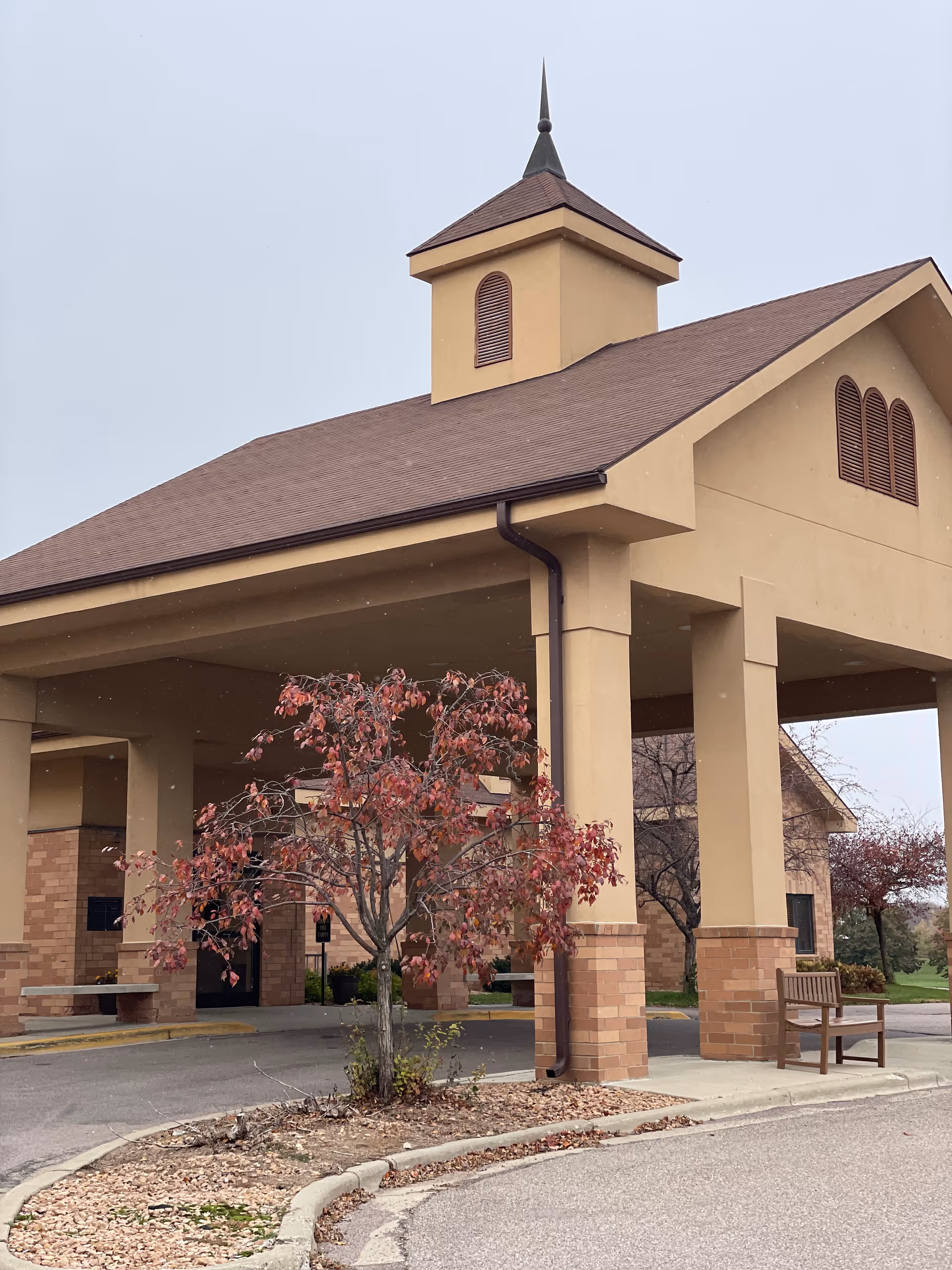 Exterior view of Oak Hills Living Center entrance with porte-cochère and landscaped tree