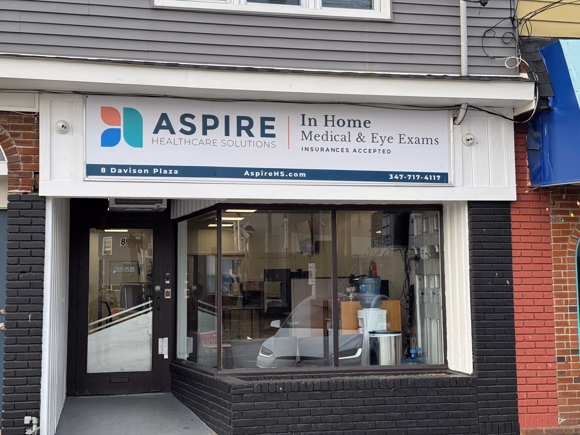 Storefront sign for Aspire Health Solutions advertising in-home medical and eye exams.