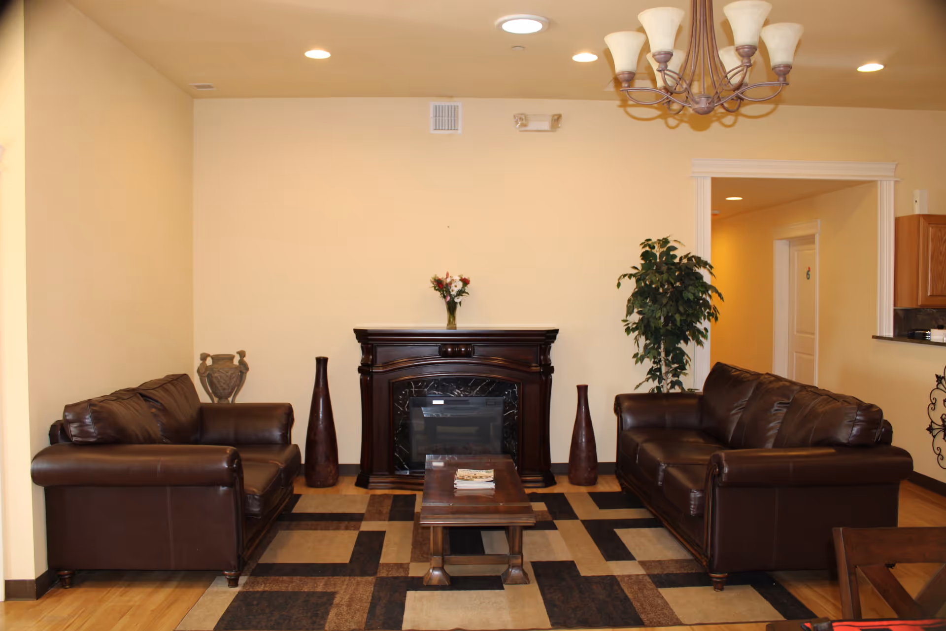 Two brown leather sofas flank a dark fireplace in a cozy, well-lit living room.