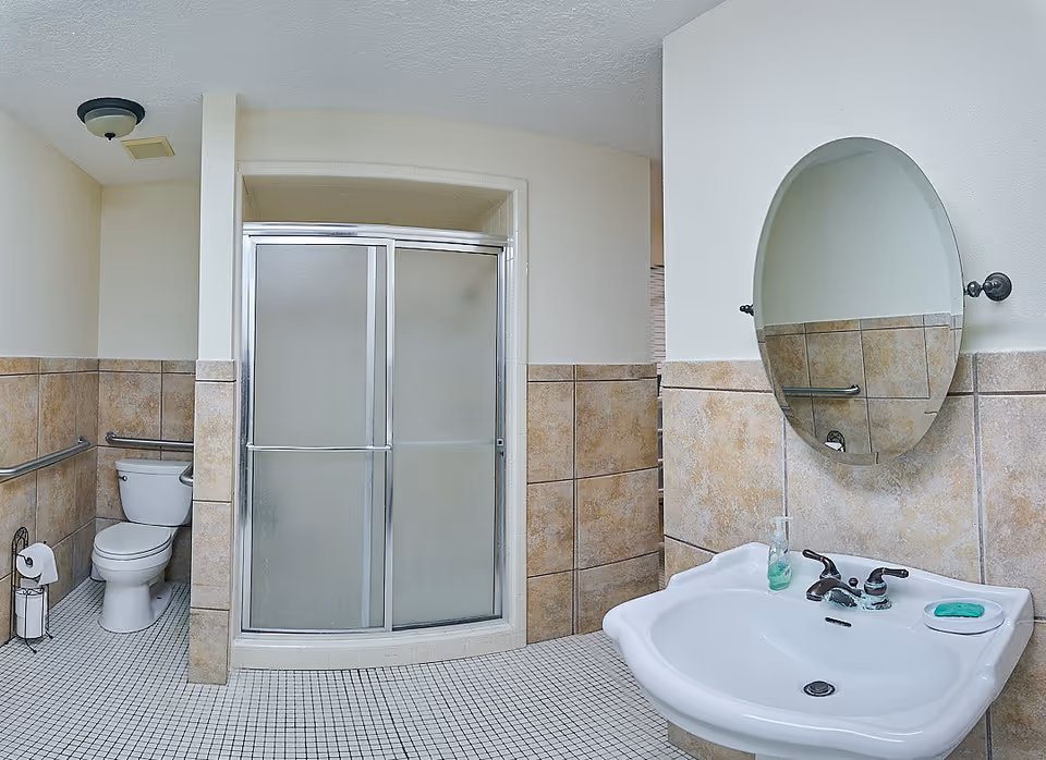 Bathroom with a shower stall, toilet, sink, and tiled walls.