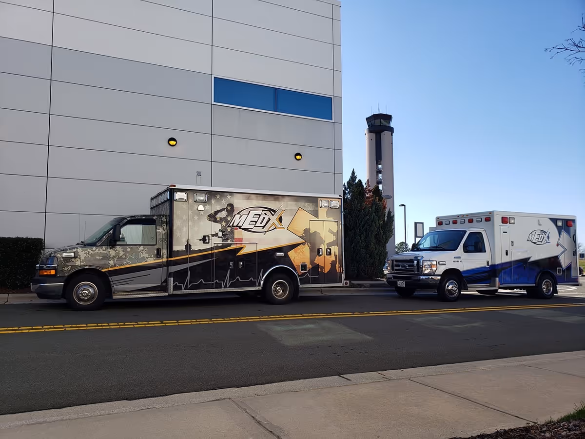 Two MedEx ambulances parked along a street in front of a modern building.