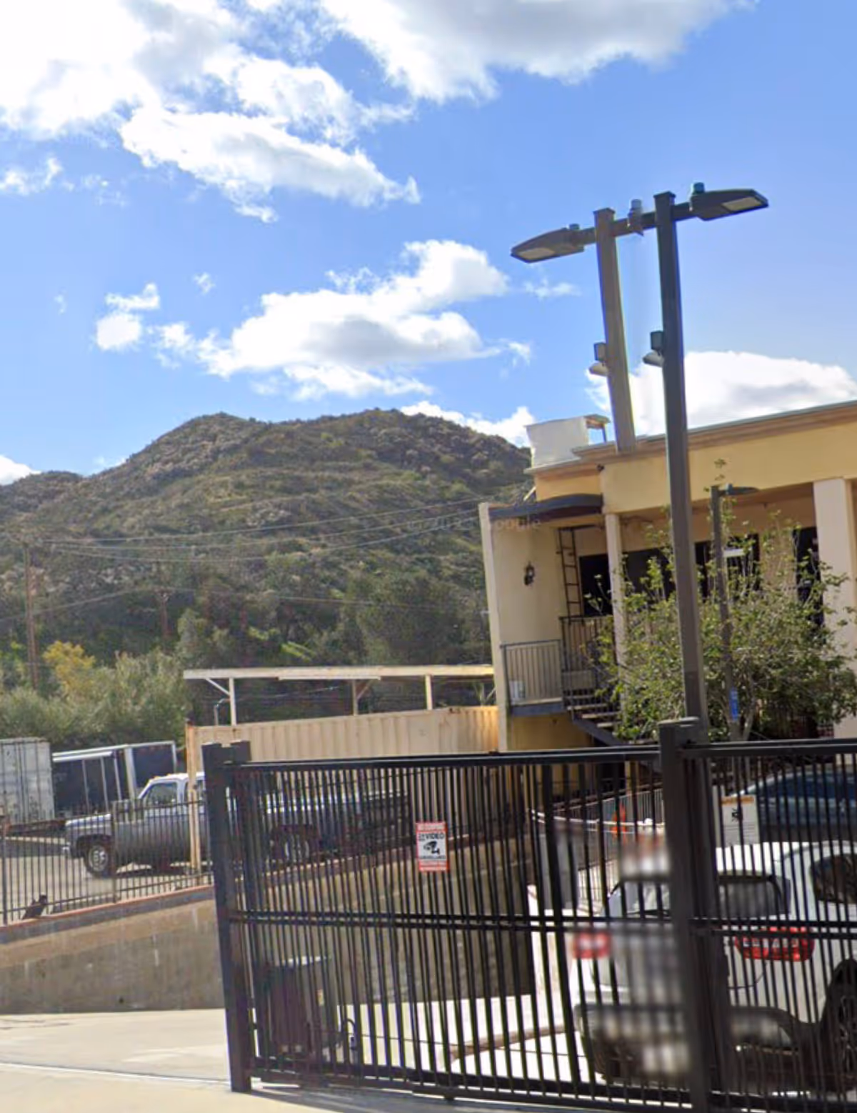 Exterior view of Oasis Home Health Care facility with gate, parked cars, and hills in background.