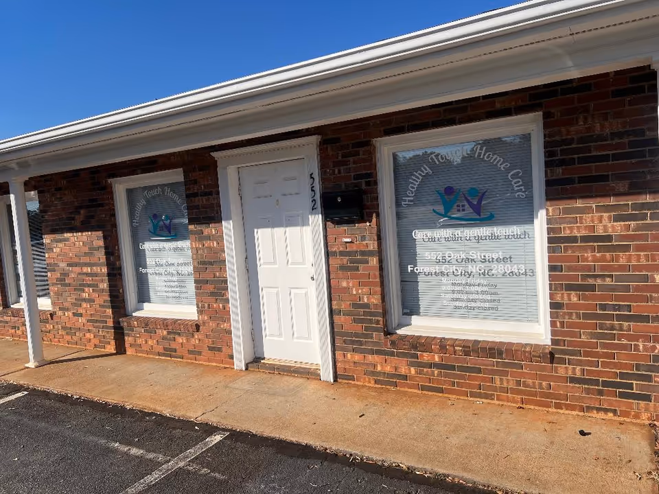 Exterior brick building with a white door and two front windows displaying signage.
