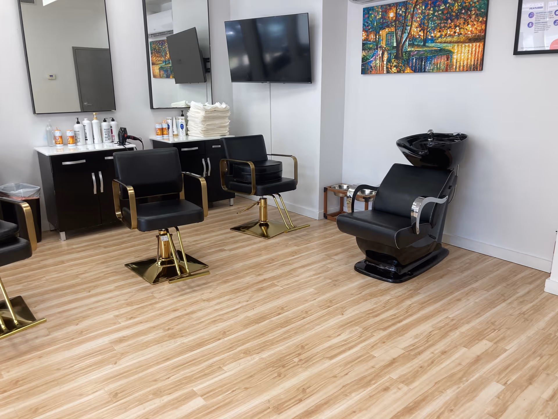 Modern salon chairs with a black washing station in a bright, wood-floored facility room.