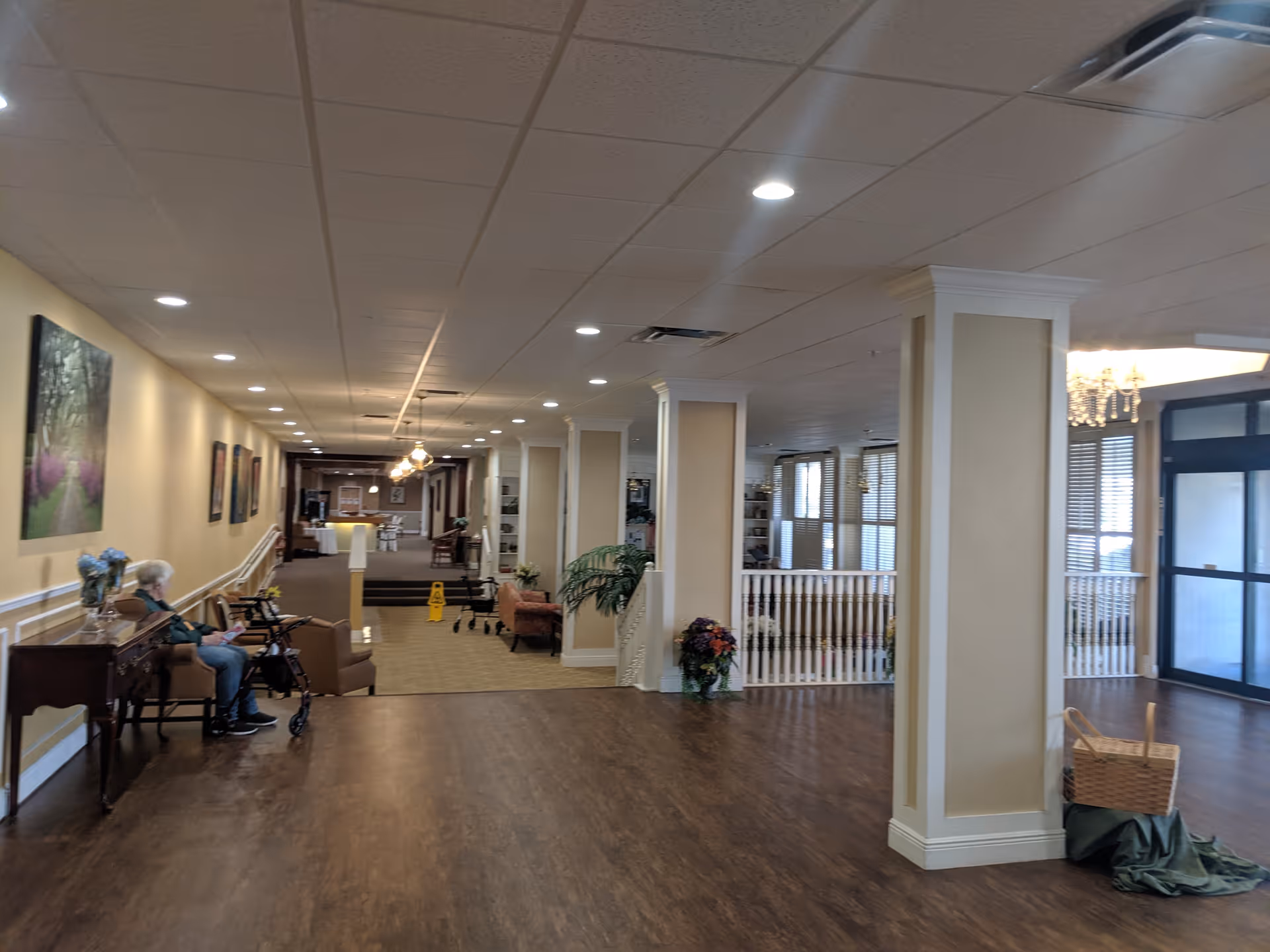 Long interior lobby at Plantation Oaks Senior Living with seating, columns, and hallways.