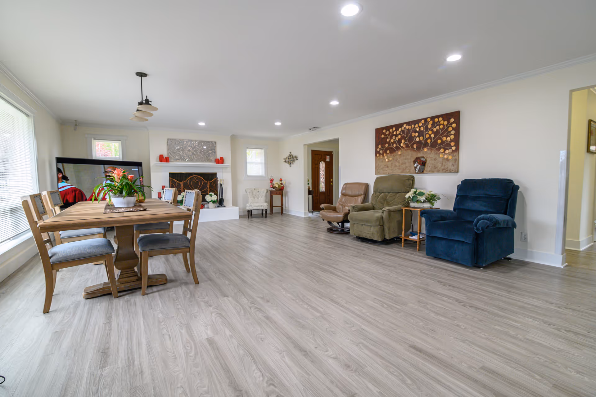 Open senior living area with dining table, fireplace, and recliners.
