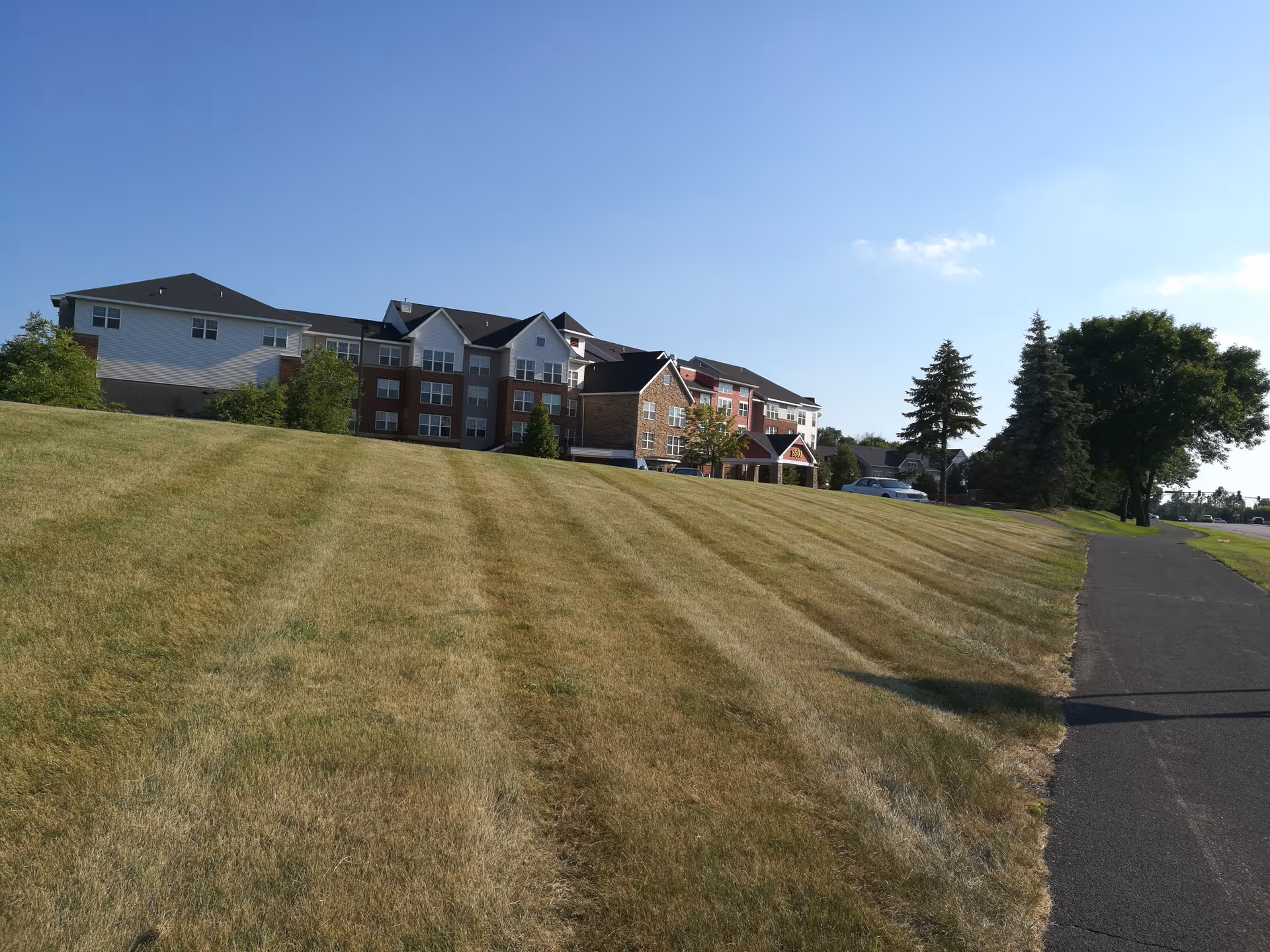 Wide view of a senior living facility exterior with a grassy slope.