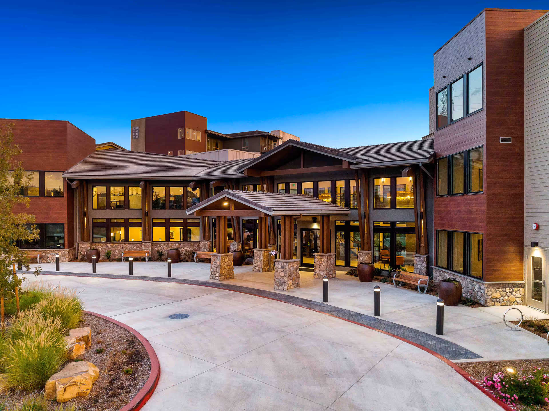 Front exterior view of Revel Folsom senior living campus with a covered entrance and glass windows.