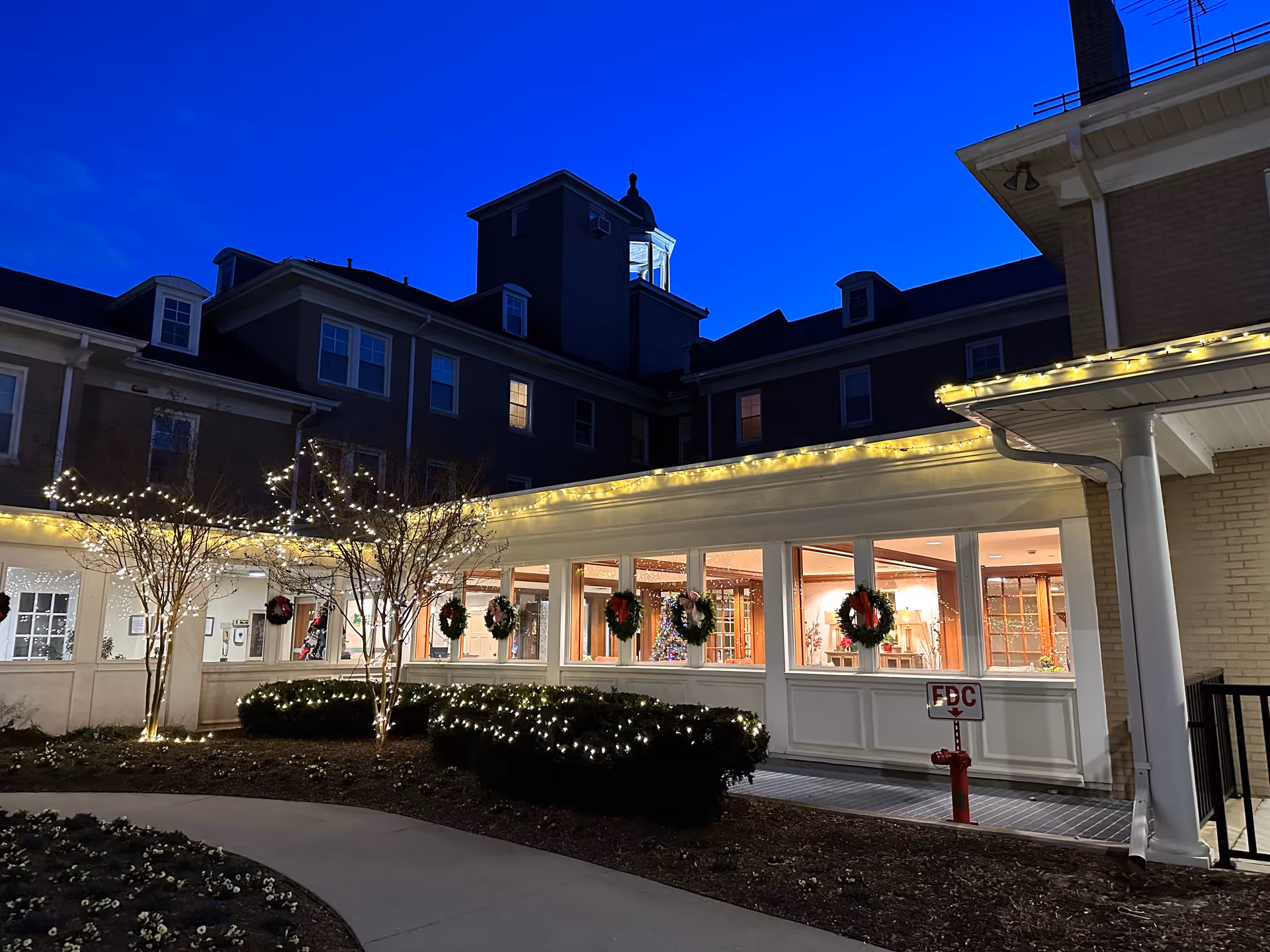 Exterior view of Glen Meadows Retirement Community with festive string lights and wreaths along the front.