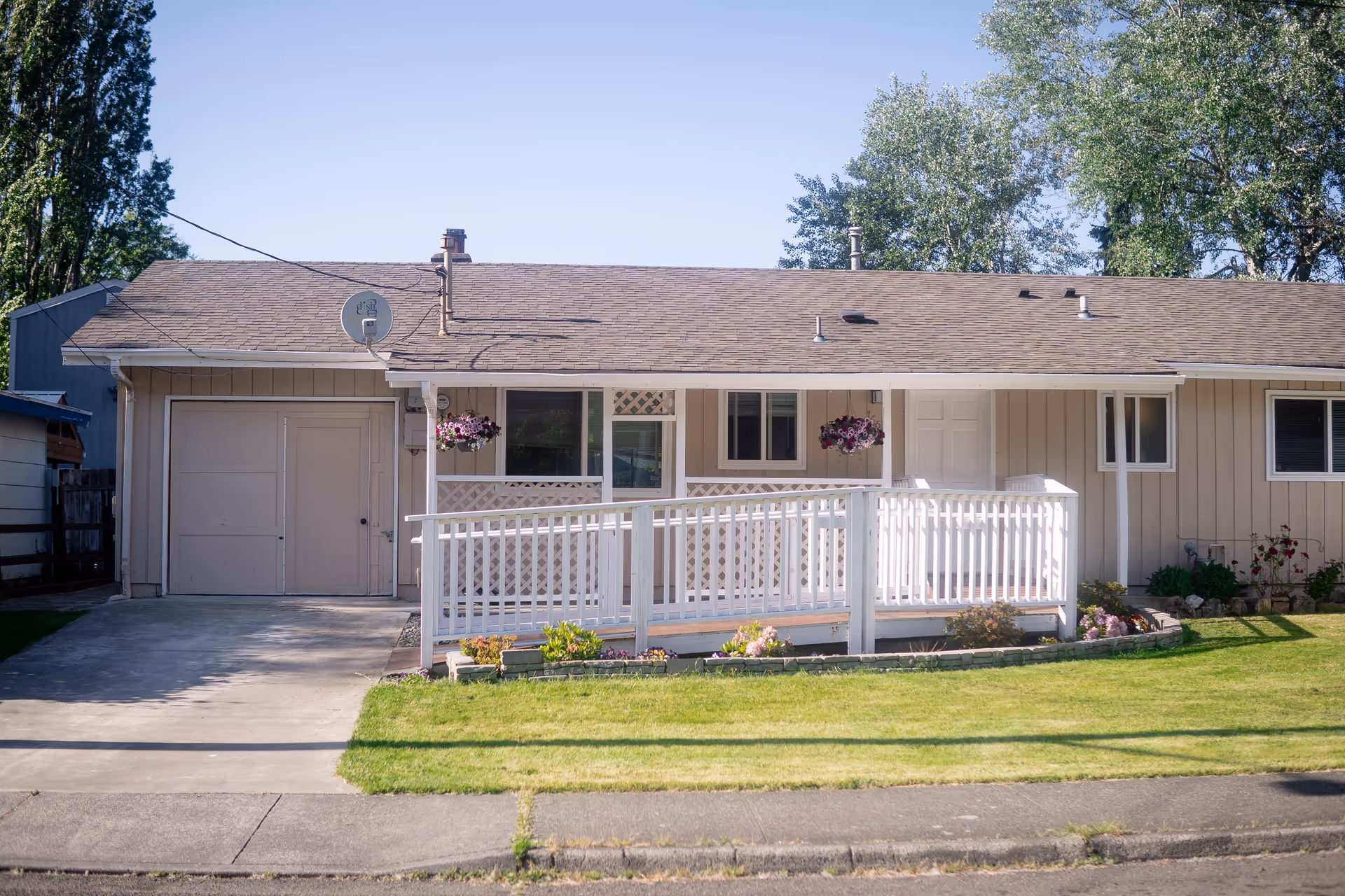 Front view of a single-story home with a white porch and hanging baskets