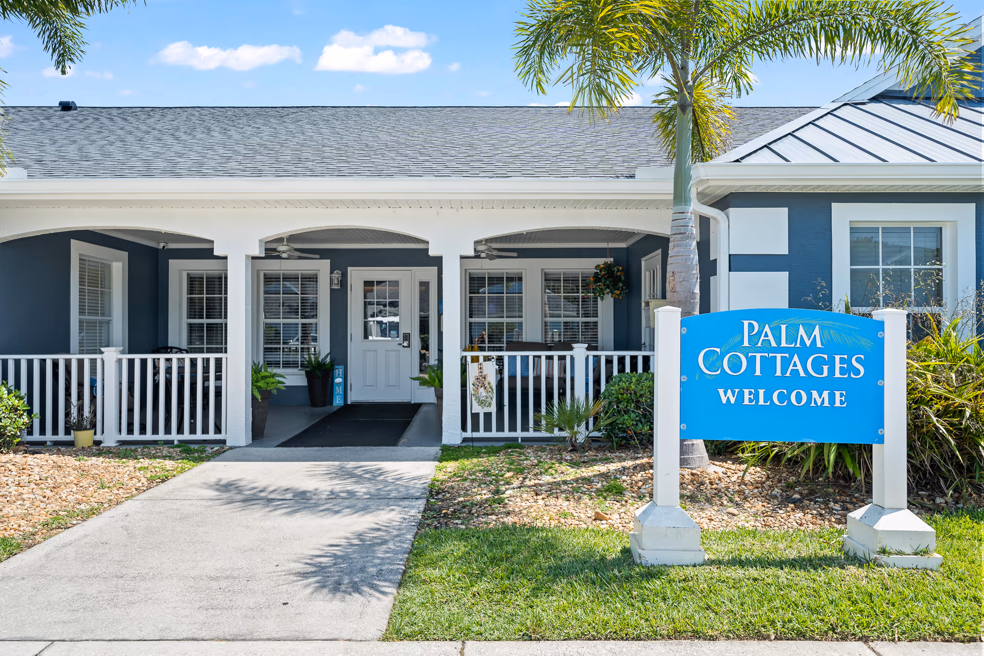 Front entrance of a senior living facility with a blue Palm Cottages sign.