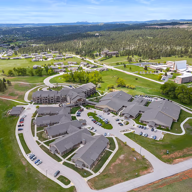 Aerial view of a sprawling senior living campus with beige buildings and green lawns.
