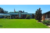 Front exterior of River Oaks Retirement Manor with a green lawn and blue sky.