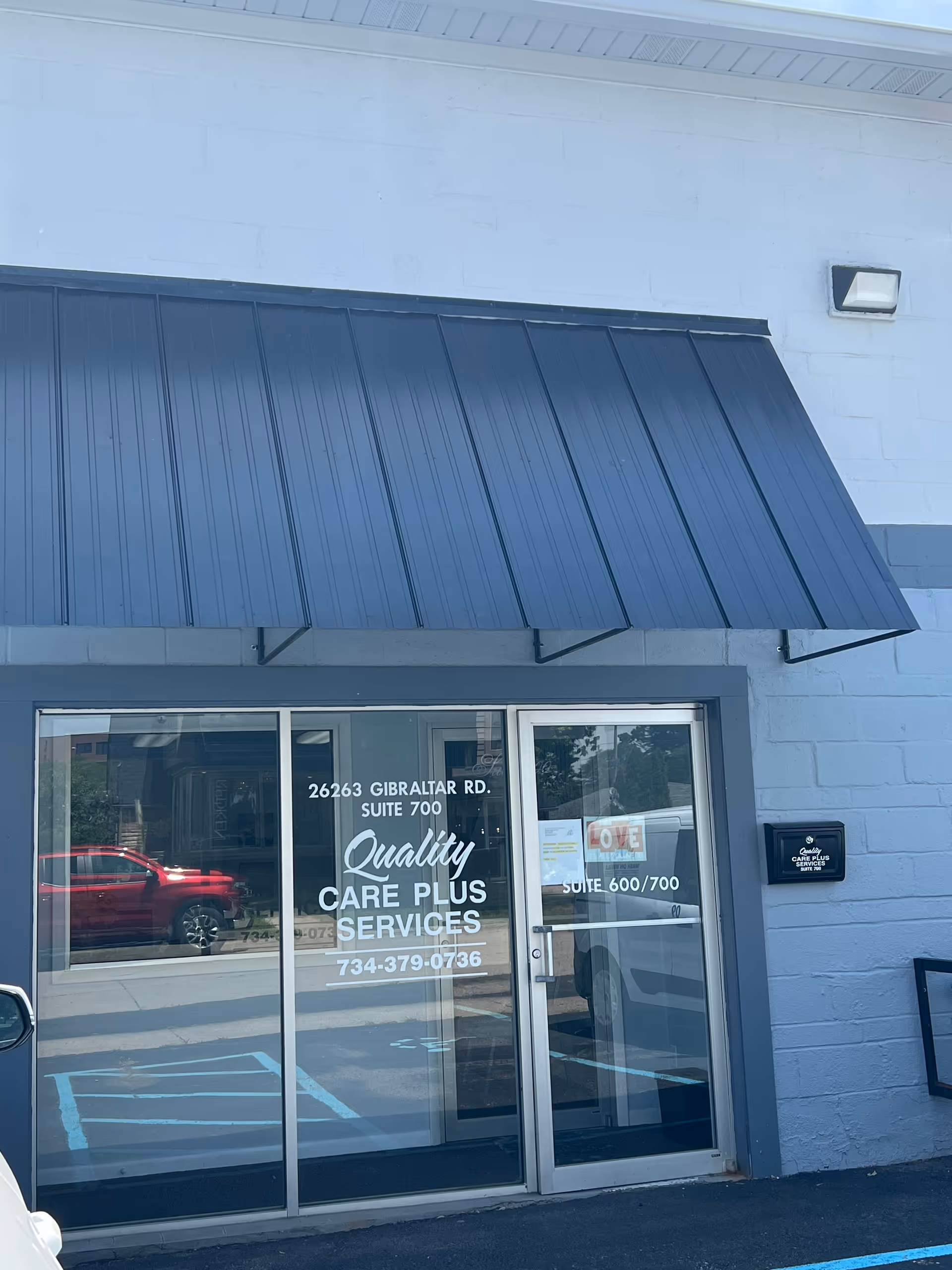 Exterior view of a building entrance with glass doors and blue awning.