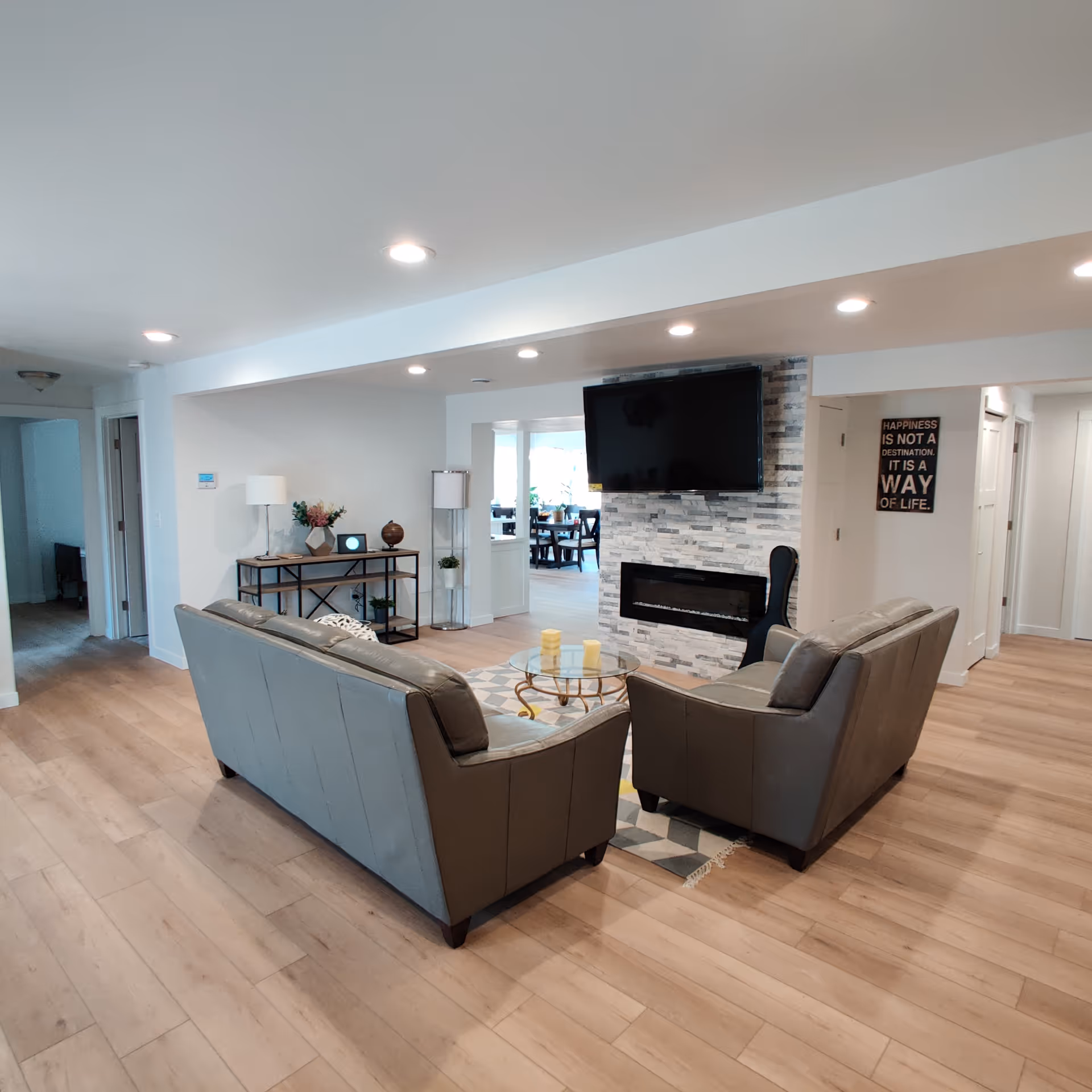 Modern open-concept living room with gray sofas, fireplace, and a wall-mounted TV.