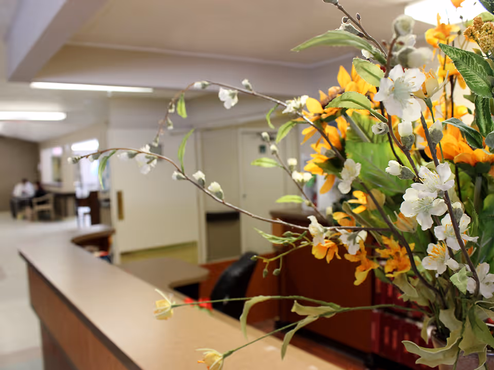 A reception desk with a large bouquet of flowers in the foreground and a hallway with seating in the background.