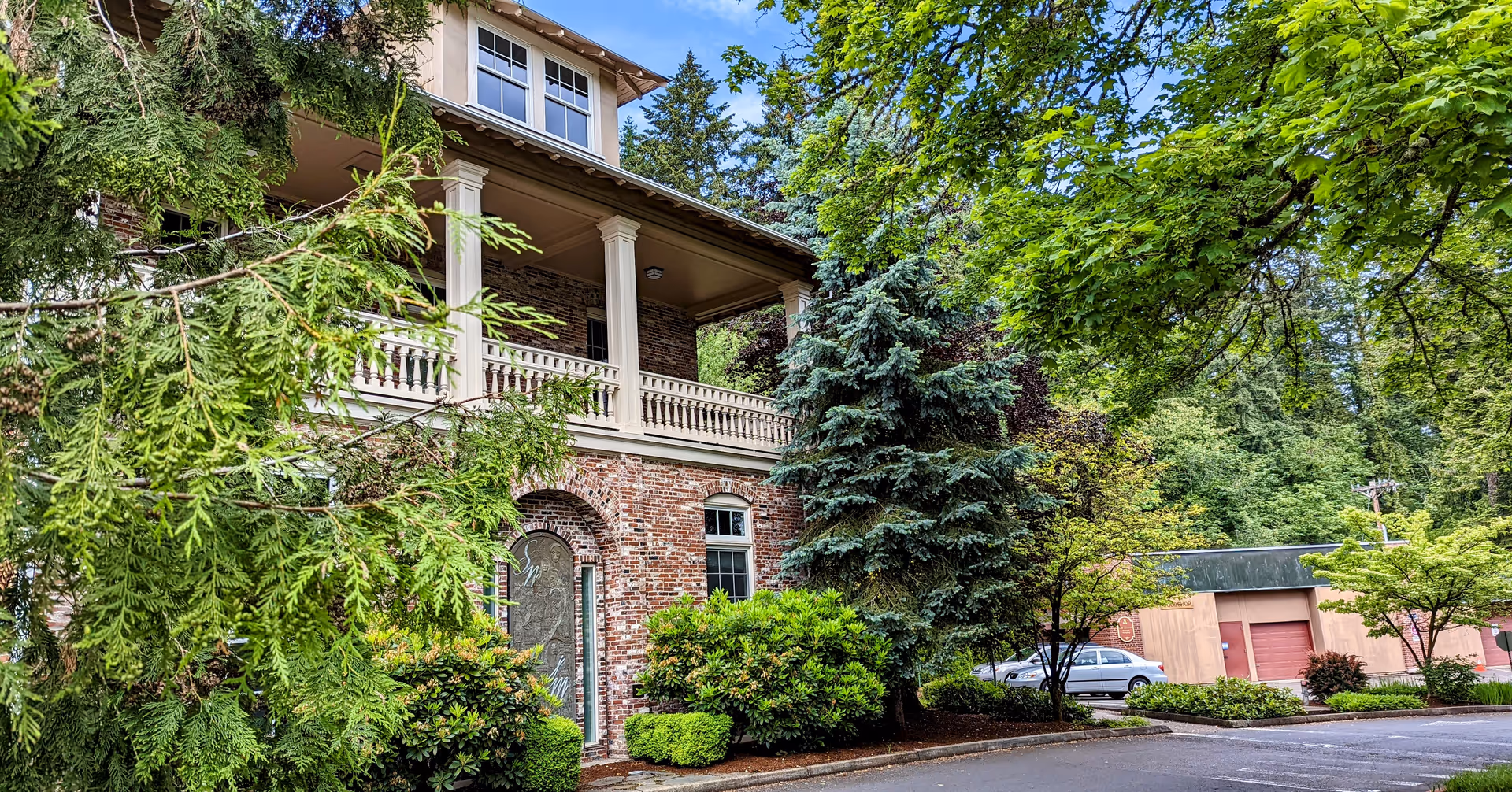Exterior view of a brick senior living facility with a covered porch and surrounding trees.