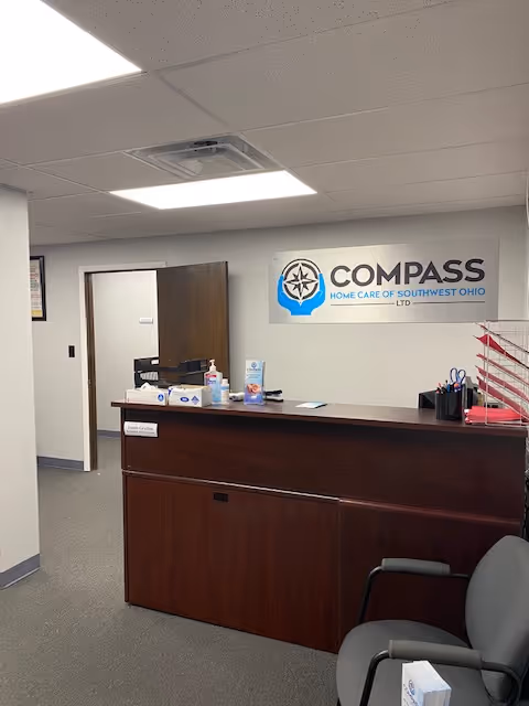Reception desk in a Compass Home Care lobby with a sign on the wall.