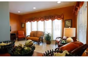 A cozy living room in warm tones with multiple sofas, chairs, and plants.