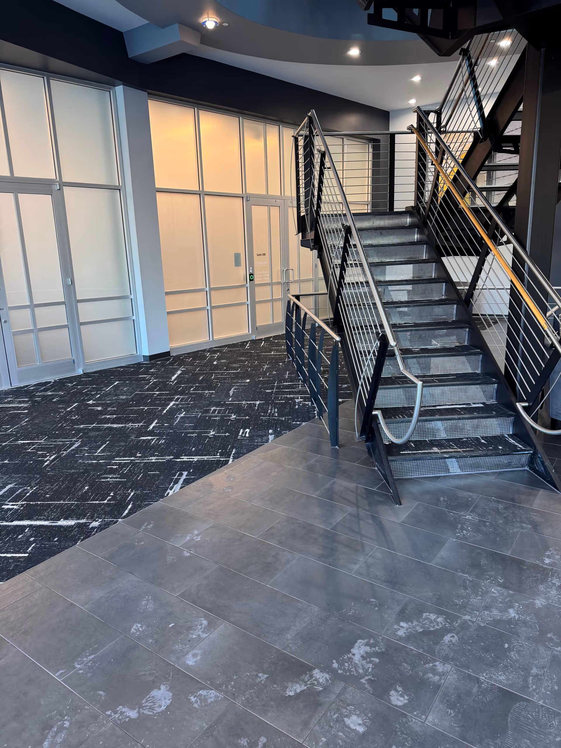 A modern interior lobby with glass walls and a metal staircase.