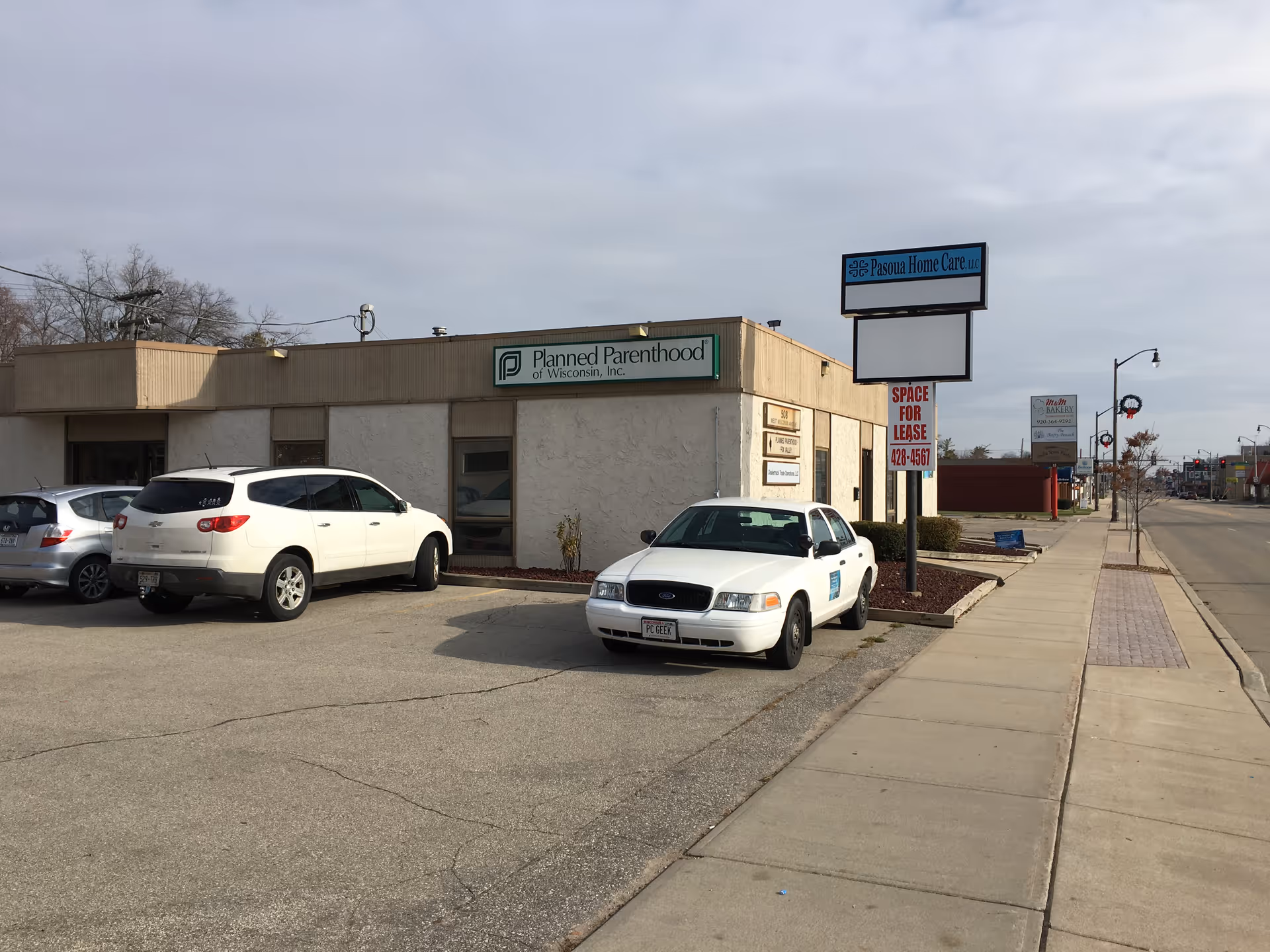 Exterior view of a beige commercial building with a Pasoua Home Care sign and parked cars.