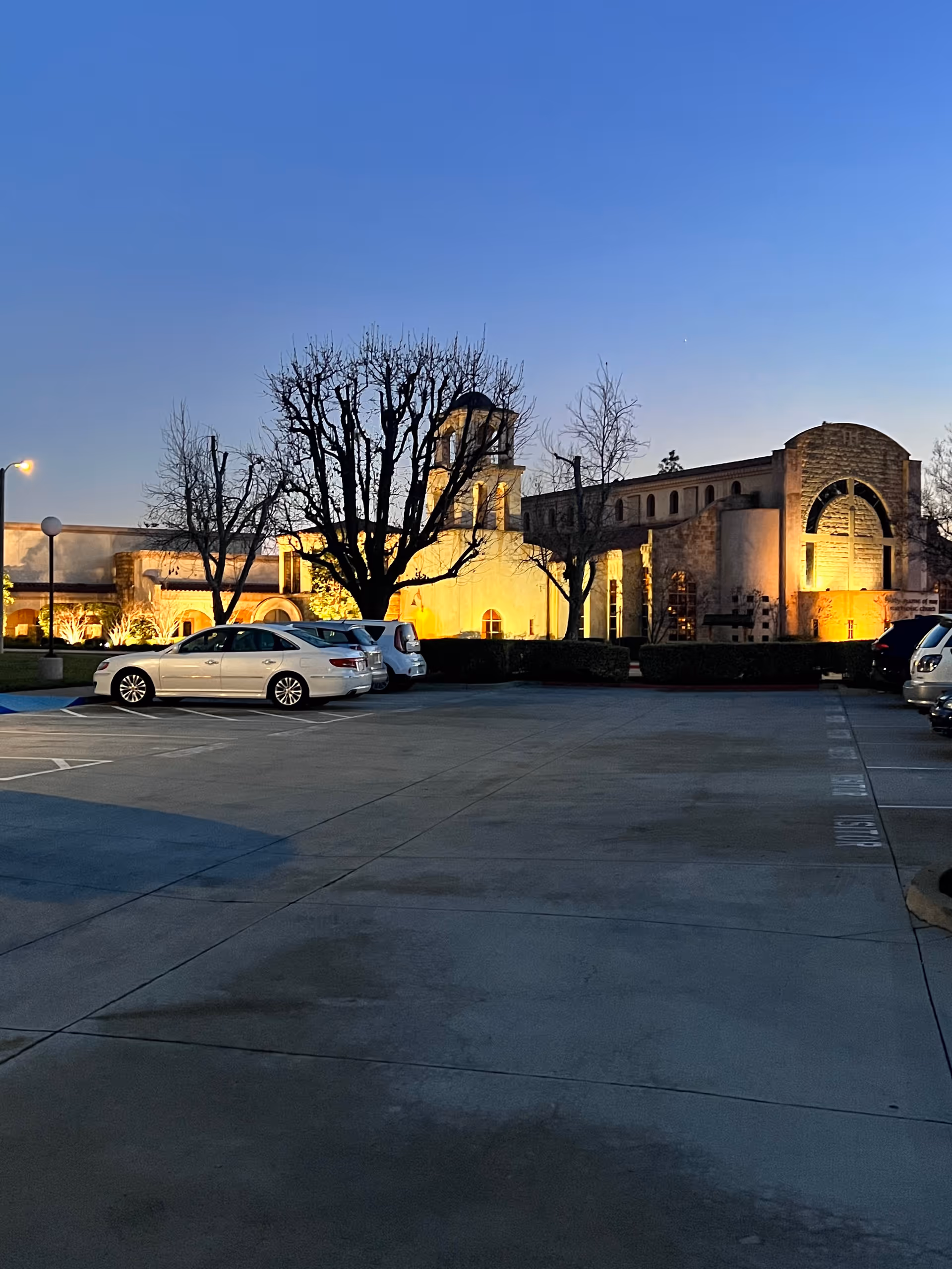 Evening exterior view of Canyon Terrace Senior Living with a parking lot and lit facade.