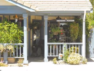 Front porch of a senior living facility with white railings and lush plants.