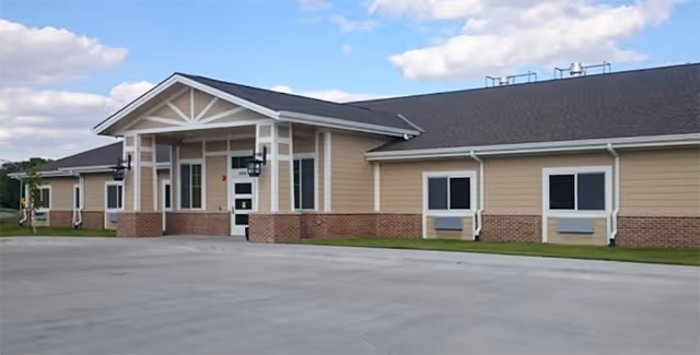 Exterior view of Hansen House senior living facility with a covered entrance and brick base.