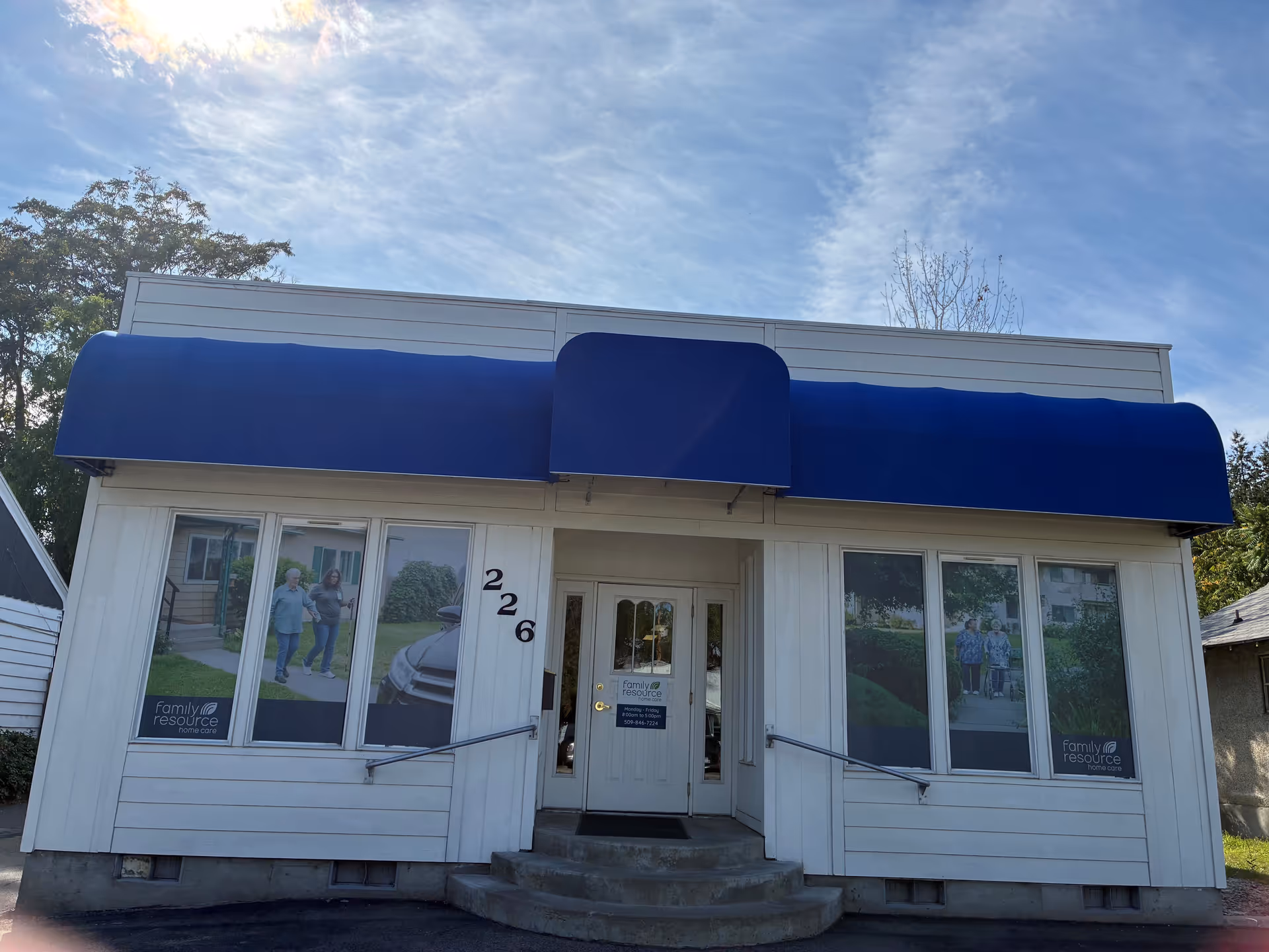 Front of a small facility with blue awnings, windows, and a glass entry door.