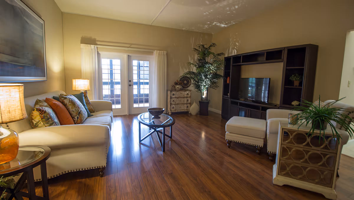 Bright living room with cream sofas, a glass coffee table, and a large entertainment unit.