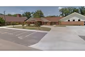Single-story brick senior living facility with parking lot and front entrance.