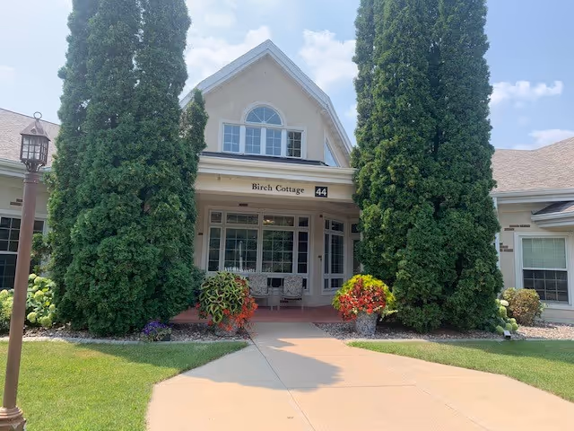 Birch Cottage entrance to The Heritage & Peabody Manor, flanked by tall evergreen trees.